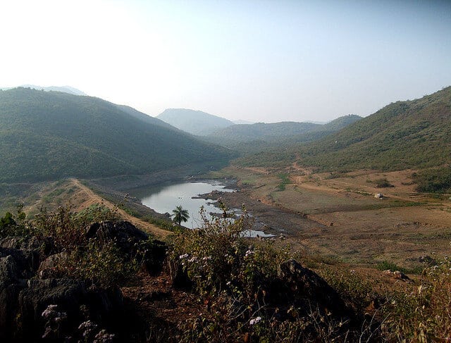 A broad view across the hills and water of Ánanda Nagar