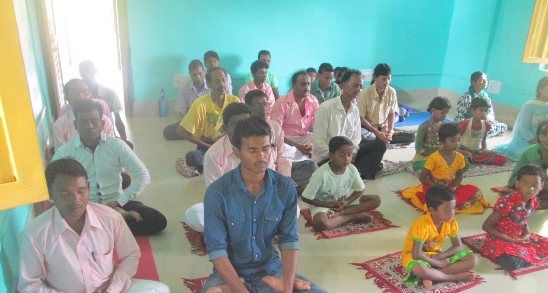 Adults and children participating in group meditation at the treatment centre